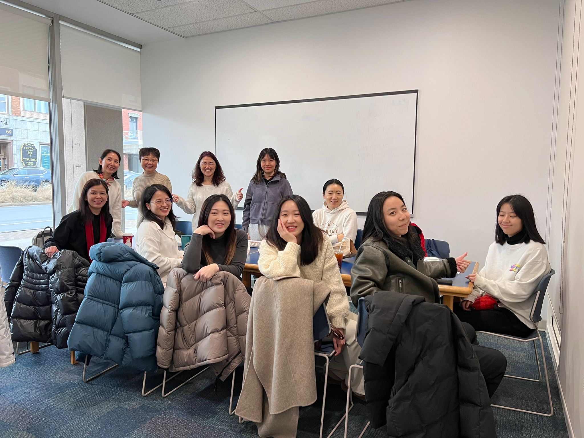 Group photo from the Chinese Women's Community of Nova Scotia New Year Resolution Coffee Chat Meetup, featuring smiling members seated in a cozy room, sharing ideas and goals for 2025.