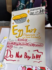 A hand-drawn sign advertises homemade egg tarts for $2.50, listing common allergens.
