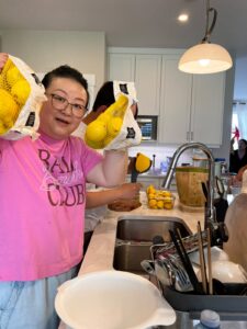 Ellie holds up lemons in a kitchen during the Lemonade Stand Project prep.