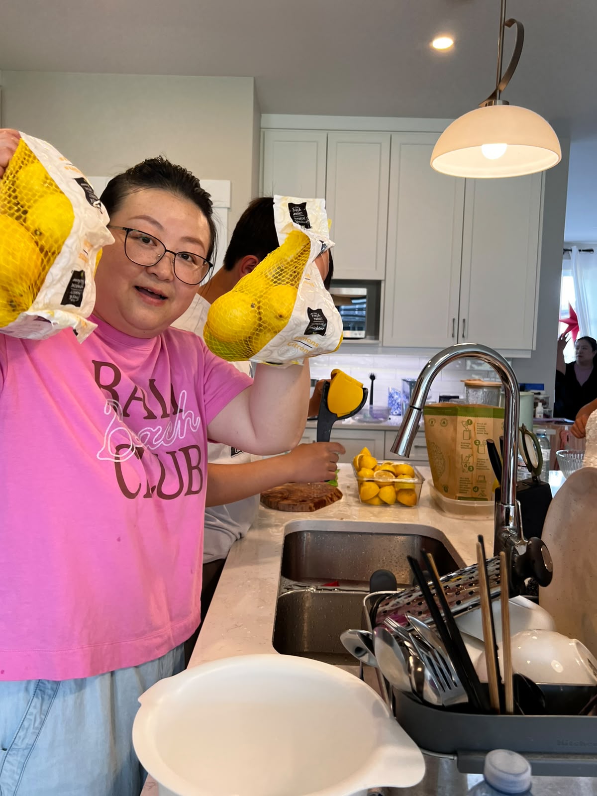Ellie holds up lemons in a kitchen during the Lemonade Stand Project prep.