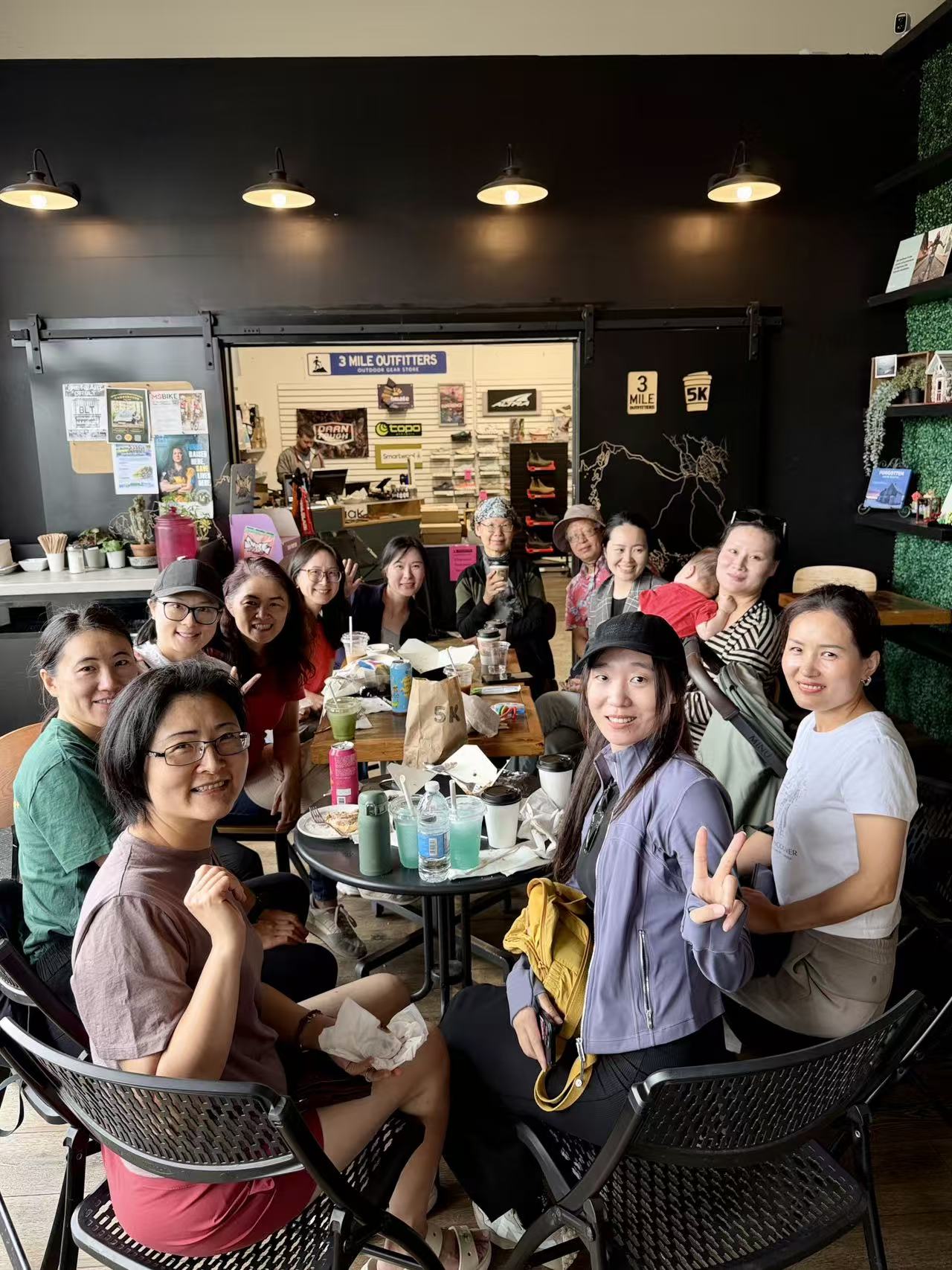 Large group seated around tables at a cafe, smiling for a group photo.